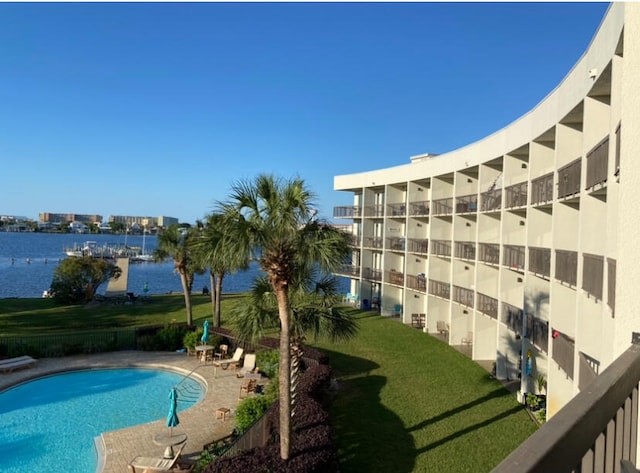 view of pool featuring a water view and a lawn