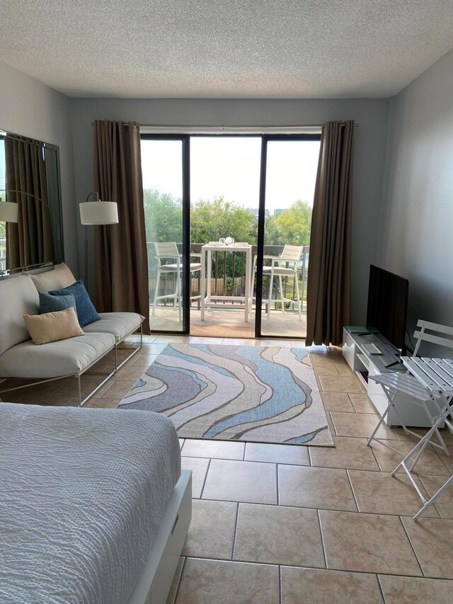 tiled bedroom with multiple windows, access to outside, and a textured ceiling