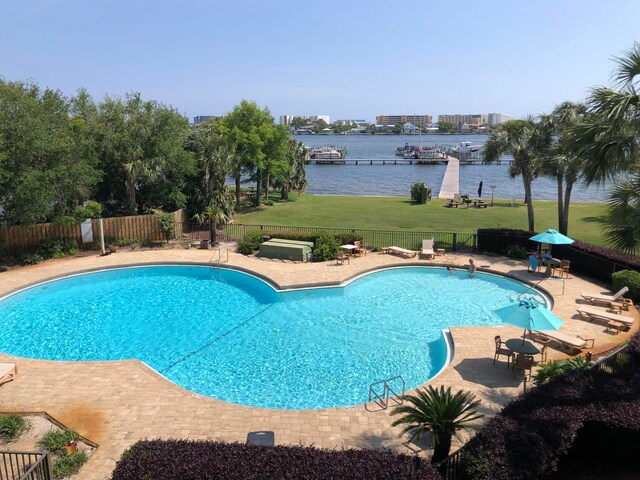 view of swimming pool featuring a water view, a yard, and a patio area