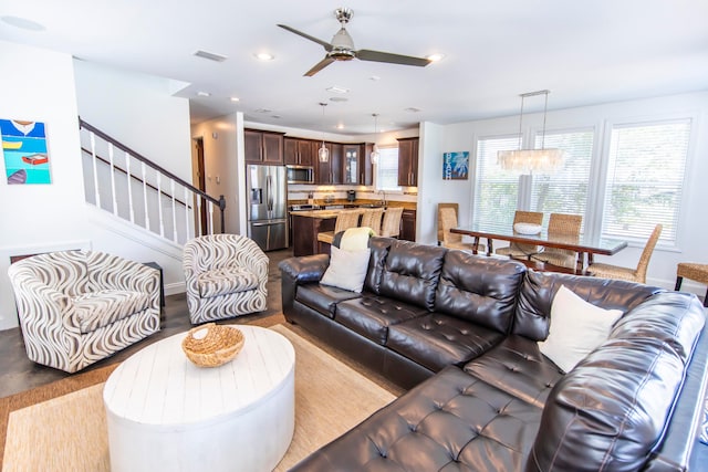 living room featuring ceiling fan with notable chandelier, light hardwood / wood-style flooring, and sink