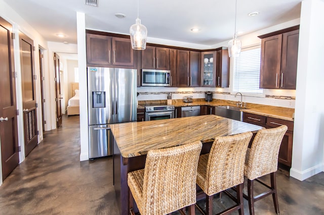 kitchen with a center island, pendant lighting, a breakfast bar, appliances with stainless steel finishes, and sink