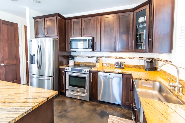 kitchen with appliances with stainless steel finishes, dark brown cabinetry, sink, and backsplash