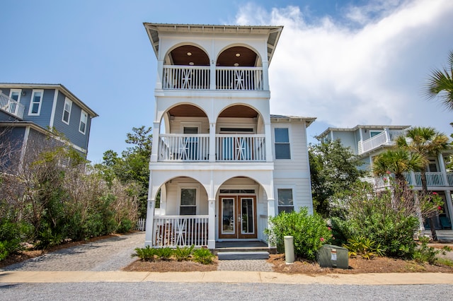 view of front of home featuring french doors, a balcony, and covered porch