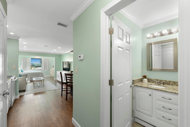 bathroom with vanity with extensive cabinet space, hardwood / wood-style flooring, and ornamental molding