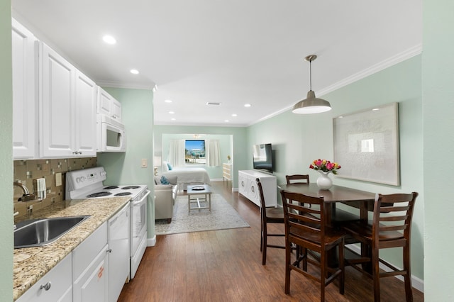 kitchen with backsplash, white appliances, dark wood-type flooring, and sink