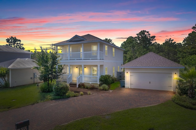 view of front facade featuring a balcony, a yard, a garage, and a porch