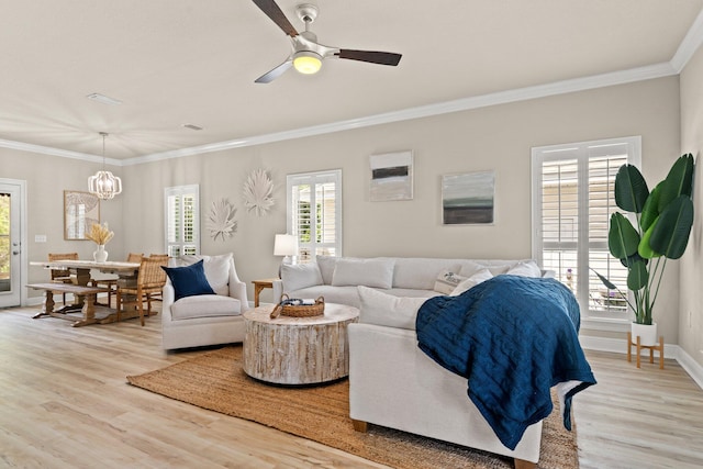 living room featuring ornamental molding, light hardwood / wood-style flooring, and ceiling fan with notable chandelier