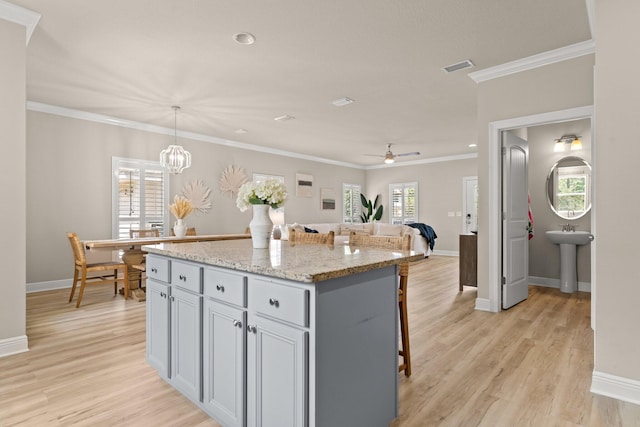 kitchen with a center island, ornamental molding, light hardwood / wood-style flooring, and hanging light fixtures