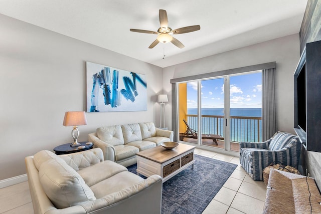 tiled living room featuring ceiling fan and a water view