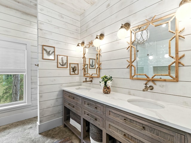 full bathroom with double vanity, wooden walls, and a sink