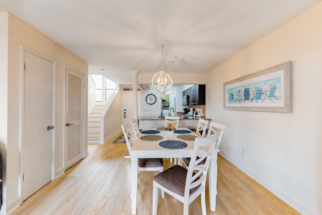 dining space with sink, light wood-type flooring, and a chandelier