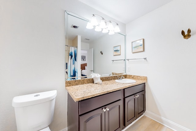 bathroom with hardwood / wood-style flooring, toilet, and vanity with extensive cabinet space