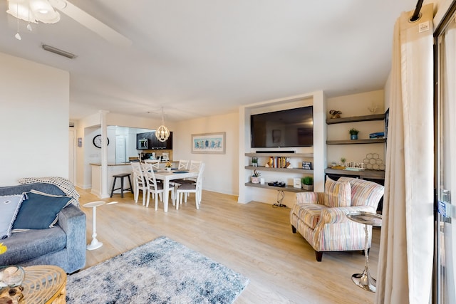 living room with ceiling fan with notable chandelier and light wood-type flooring