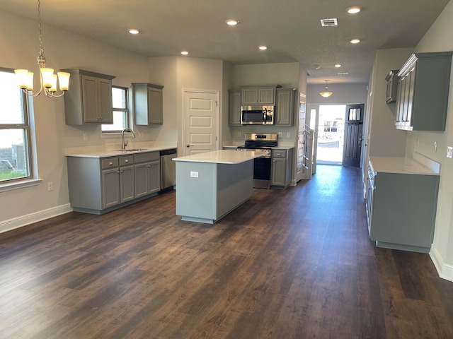 kitchen with sink, a center island, gray cabinets, appliances with stainless steel finishes, and dark hardwood / wood-style flooring