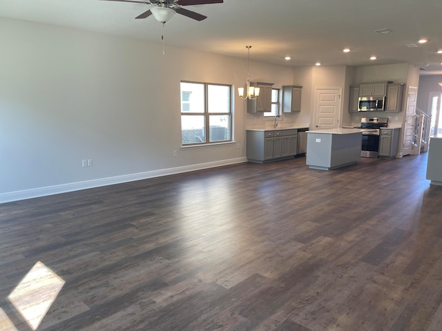 unfurnished living room featuring sink, ceiling fan with notable chandelier, and dark hardwood / wood-style flooring