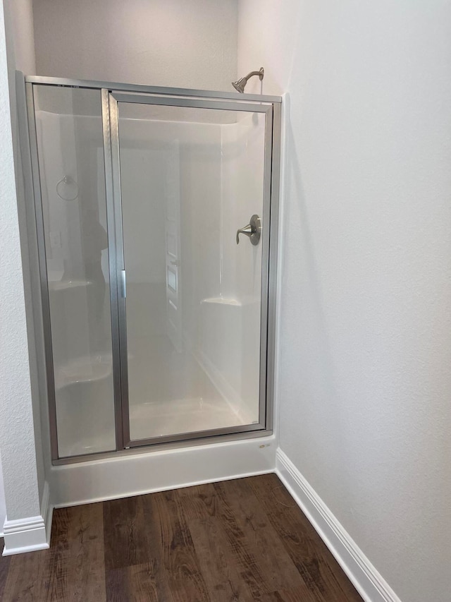 bathroom featuring a shower with shower door and wood-type flooring