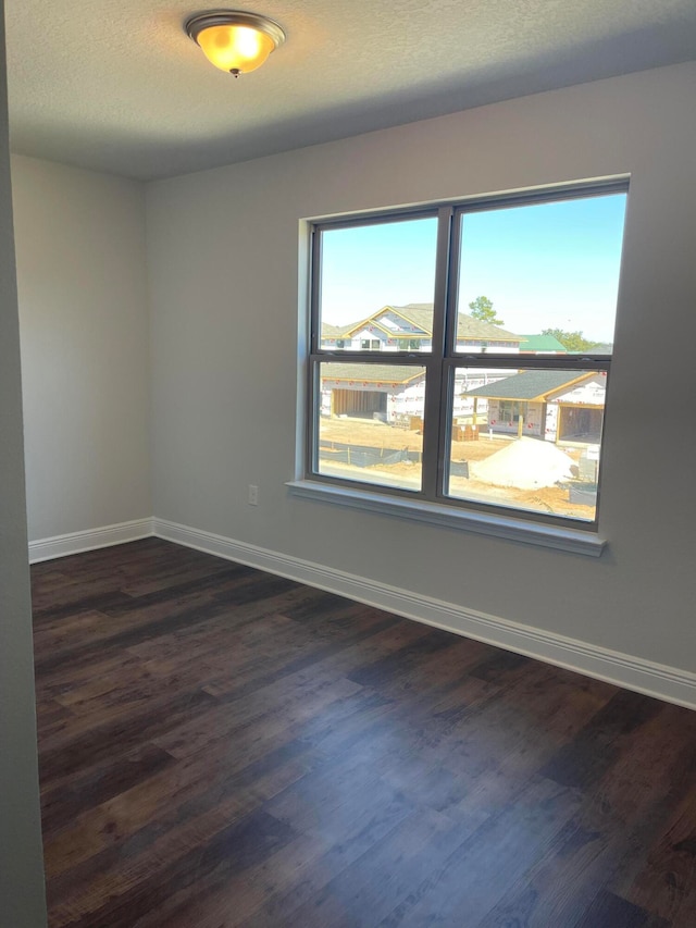 unfurnished room featuring dark wood-type flooring and a textured ceiling