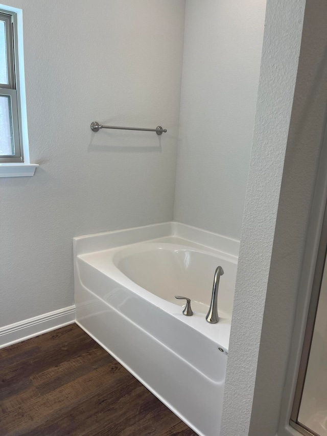 bathroom with a tub and wood-type flooring