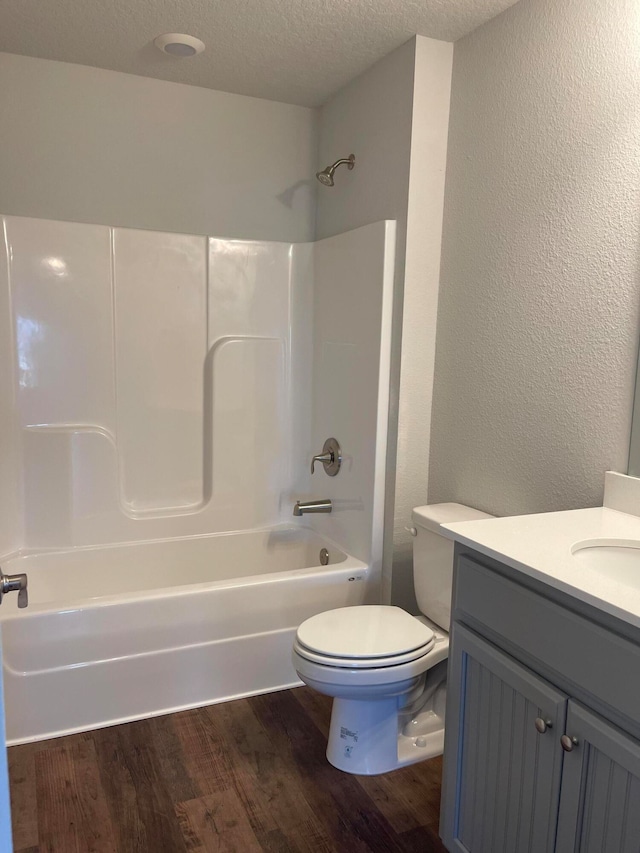 full bathroom featuring bathtub / shower combination, hardwood / wood-style floors, a textured ceiling, toilet, and vanity