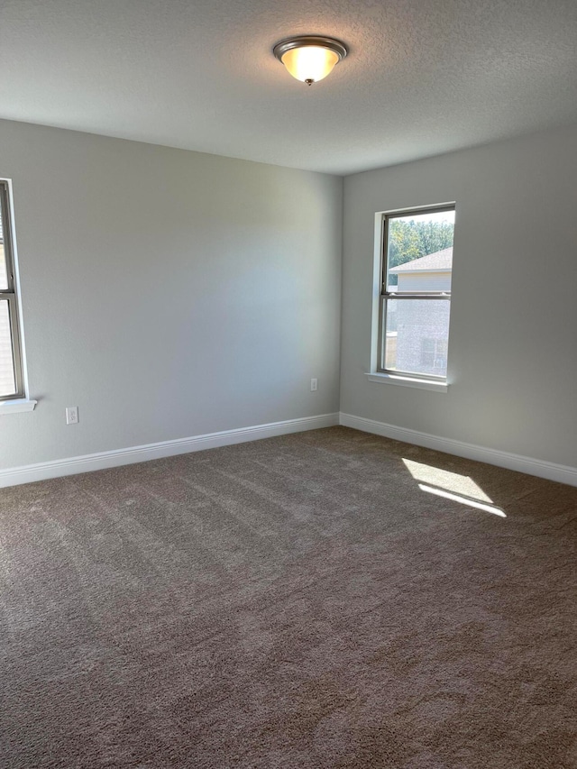 carpeted empty room with a textured ceiling