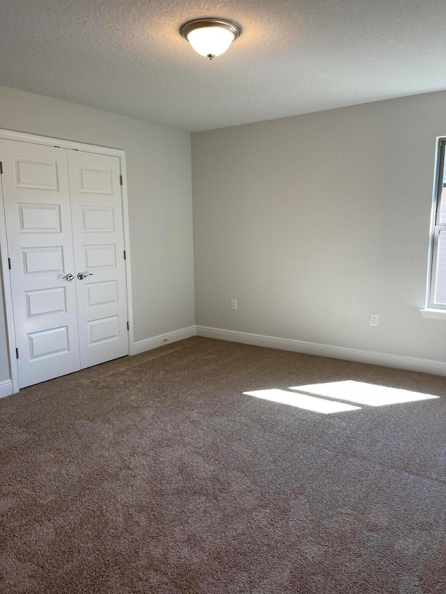 empty room with carpet floors and a textured ceiling