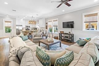 living room with wood-type flooring, ceiling fan, a healthy amount of sunlight, and crown molding