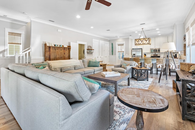 living room with crown molding, ceiling fan, and light wood-type flooring