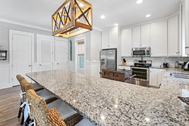 kitchen featuring light stone counters, white cabinets, dark wood-type flooring, stainless steel appliances, and pendant lighting