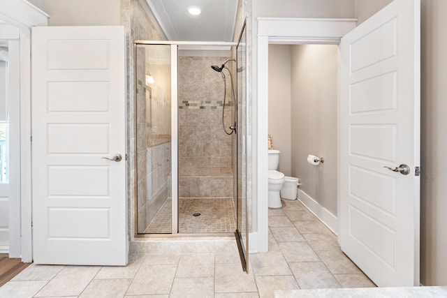 bathroom featuring a shower with door, toilet, and tile floors