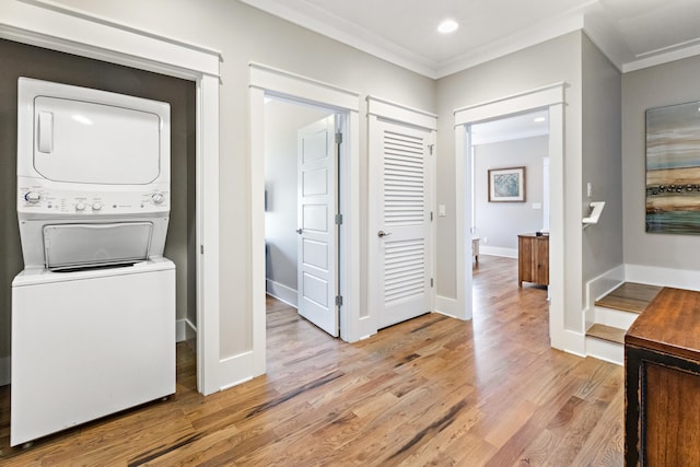 interior space featuring ornamental molding, stacked washer and clothes dryer, and light wood-type flooring