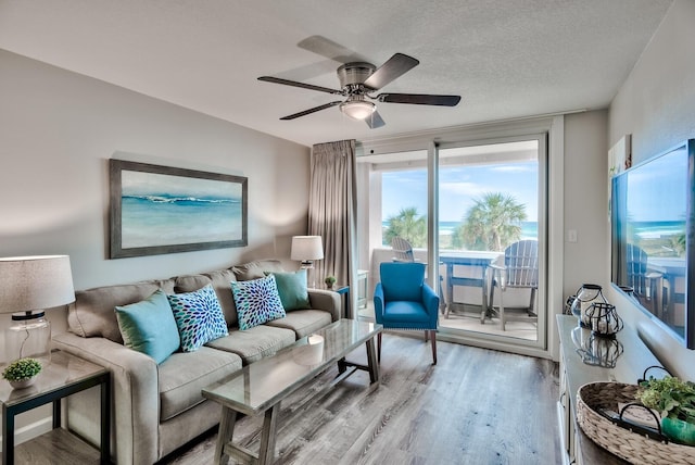 living room featuring a wealth of natural light, hardwood / wood-style floors, ceiling fan, and a textured ceiling