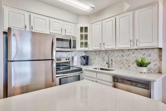 kitchen with sink, white cabinets, backsplash, and stainless steel appliances