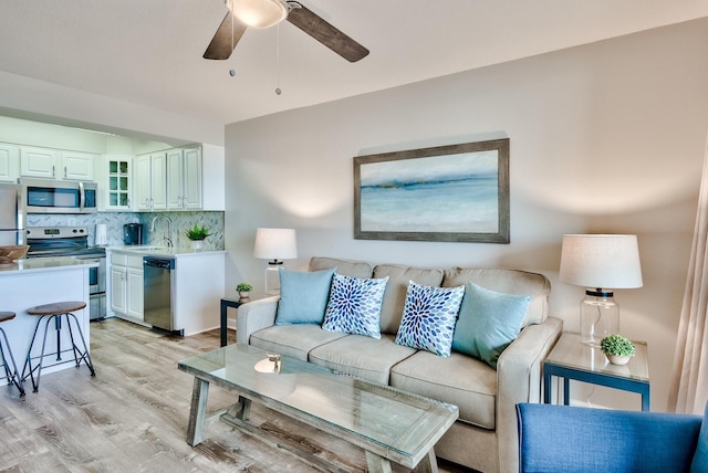 living room with light hardwood / wood-style floors, sink, and ceiling fan