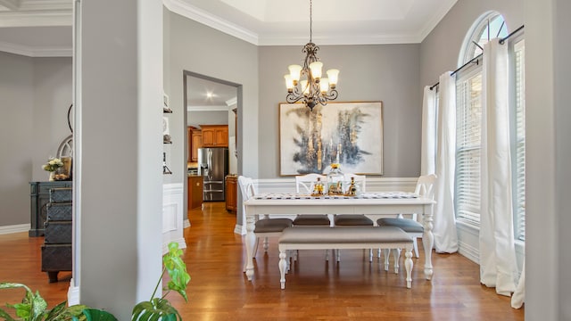 dining space featuring light wood-type flooring, ornamental molding, and a chandelier