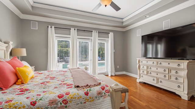 bedroom with a raised ceiling, ceiling fan, light hardwood / wood-style flooring, and ornamental molding