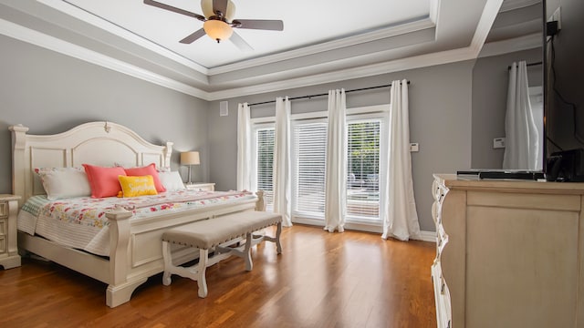 bedroom with hardwood / wood-style flooring, ceiling fan, a raised ceiling, and ornamental molding