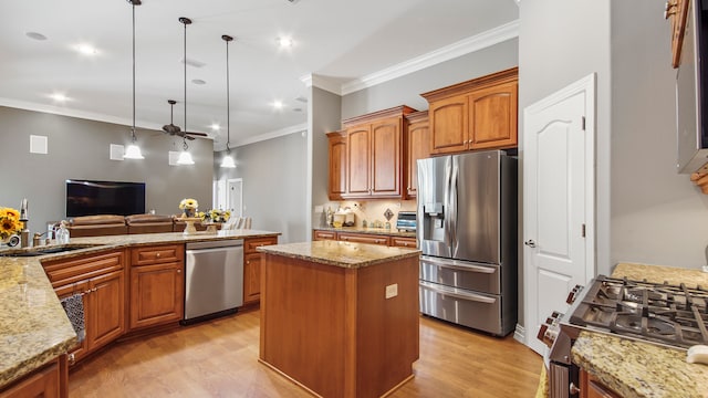 kitchen with sink, ceiling fan, decorative light fixtures, a kitchen island, and stainless steel appliances