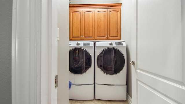 laundry room with cabinets, light tile patterned floors, and washer and clothes dryer