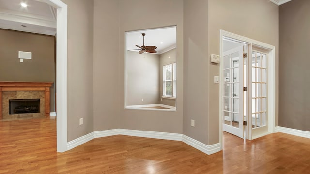 unfurnished dining area featuring a fireplace, light hardwood / wood-style flooring, ceiling fan, and ornamental molding