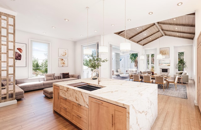 kitchen with light wood-style floors, open floor plan, a sink, and light brown cabinetry