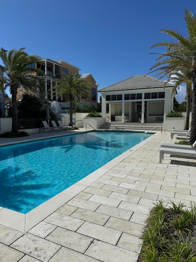 pool with a patio area, an exterior structure, an outdoor structure, and fence