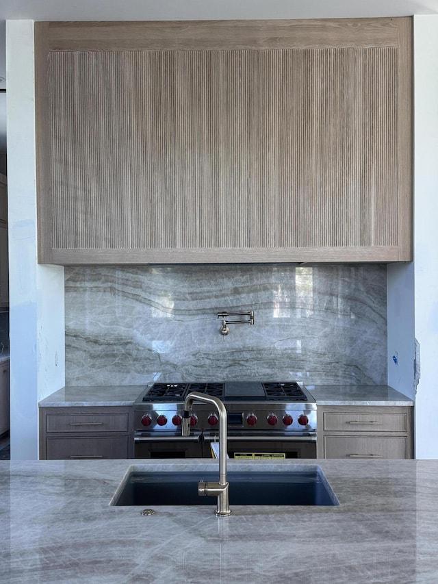 kitchen featuring light stone countertops, tasteful backsplash, and a sink