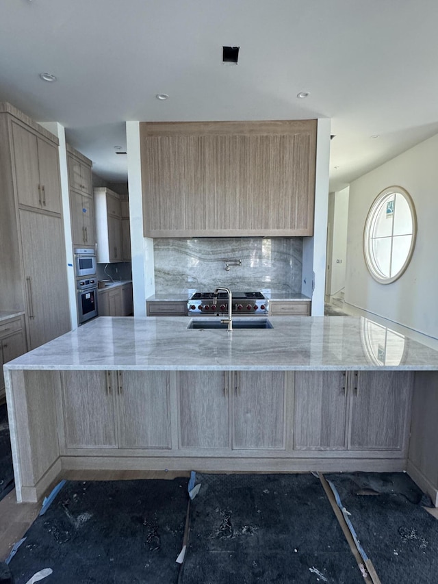 kitchen with light stone countertops, backsplash, and light brown cabinetry