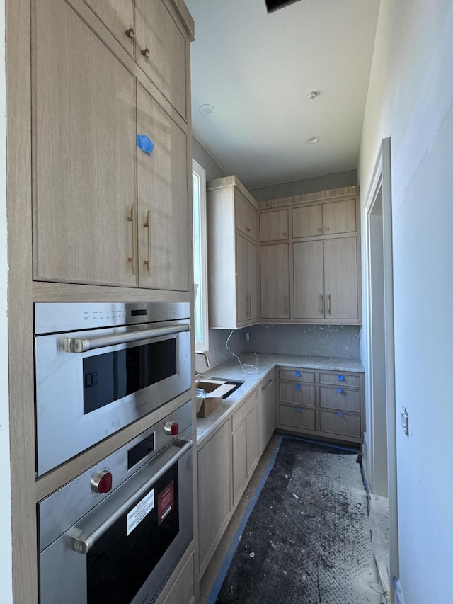 kitchen with oven, light countertops, a sink, and light brown cabinetry