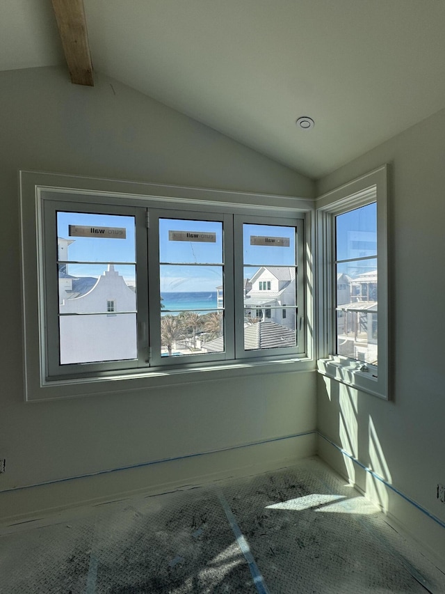 spare room featuring lofted ceiling with beams and a healthy amount of sunlight