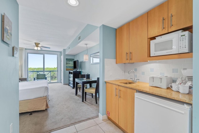 kitchen featuring sink, ceiling fan, tasteful backsplash, and white microwave