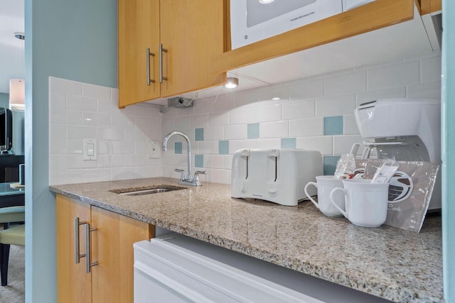 kitchen featuring tasteful backsplash, sink, and light stone counters