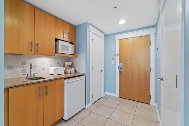 kitchen with white appliances, light tile flooring, tasteful backsplash, light stone counters, and sink