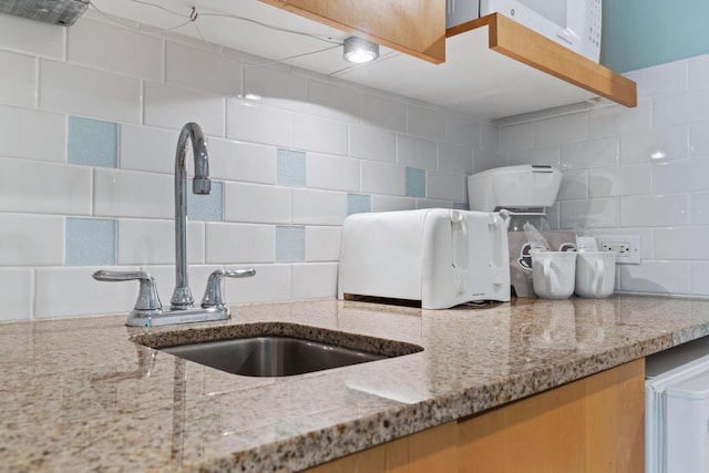 kitchen featuring backsplash, sink, and light stone countertops