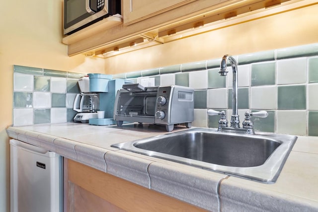 kitchen featuring stainless steel microwave, sink, refrigerator, and tasteful backsplash